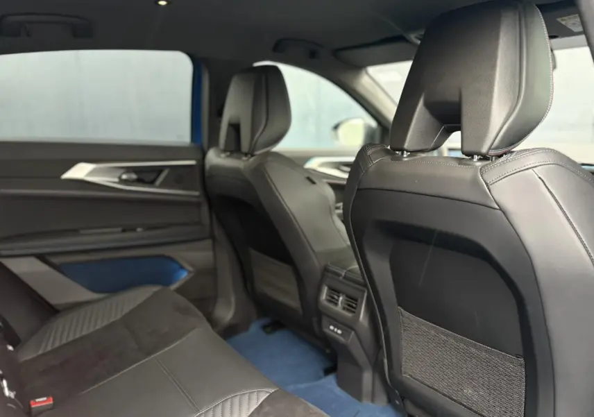 Vue intérieure arrière droite du Renault Rafale 4X4 E-Tech bleu sommet, avec sellerie noire et inserts bleus raffinés.