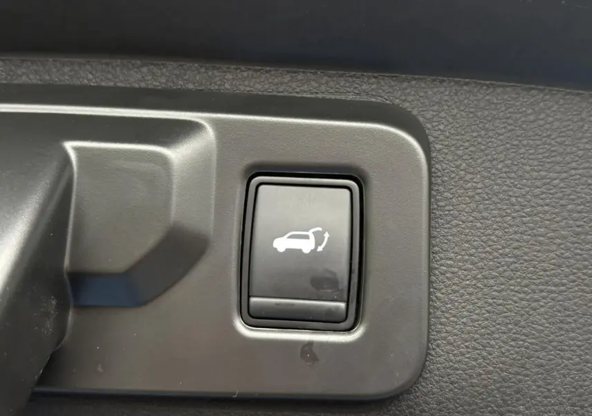 Bouton intérieur noir pour ouverture motorisée du hayon sur Renault Rafale 4x4 E-Tech bleu sommet, vue rapprochée.