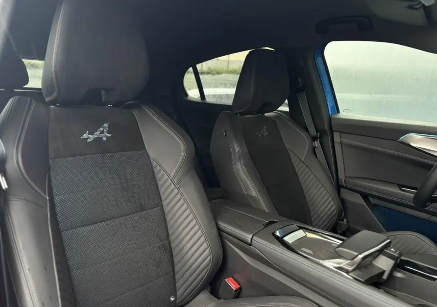 Vue intérieure côté droit montrant les sièges avant noirs avec logo Alpine brodé et surpiqûres contrastées.