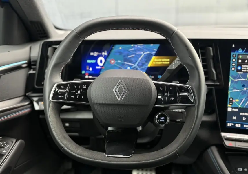 Vue rapprochée du volant Alcantara et du tableau de bord numérique du Renault Rafale 4x4 E-Tech bleu sommet.