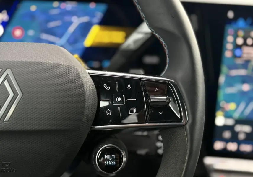 Gros plan sur le volant noir avec commandes tactiles et bouton Multi-Sense du Renault Rafale 4x4 E-Tech.