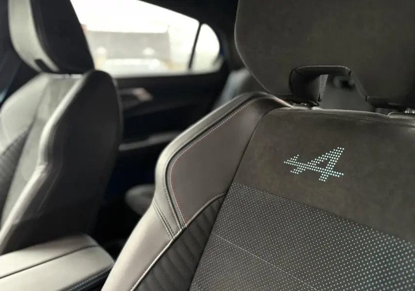 Gros plan sur les sièges avant en Alcantara noir avec surpiqûres tricolores et logo « A » lumineux du Renault Rafale.