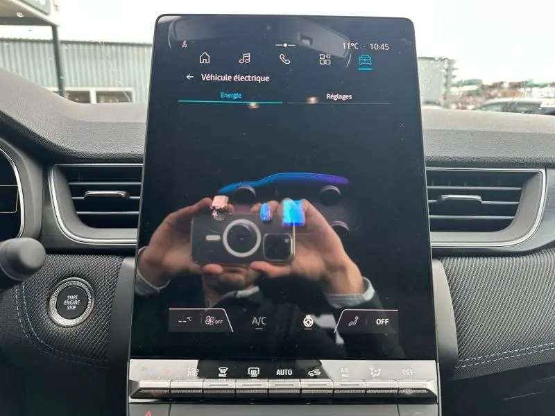 Écran tactile central du Renault Captur 1.8 E-Tech 2026, affichant les réglages énergie et véhicule électrique, intérieur noir.