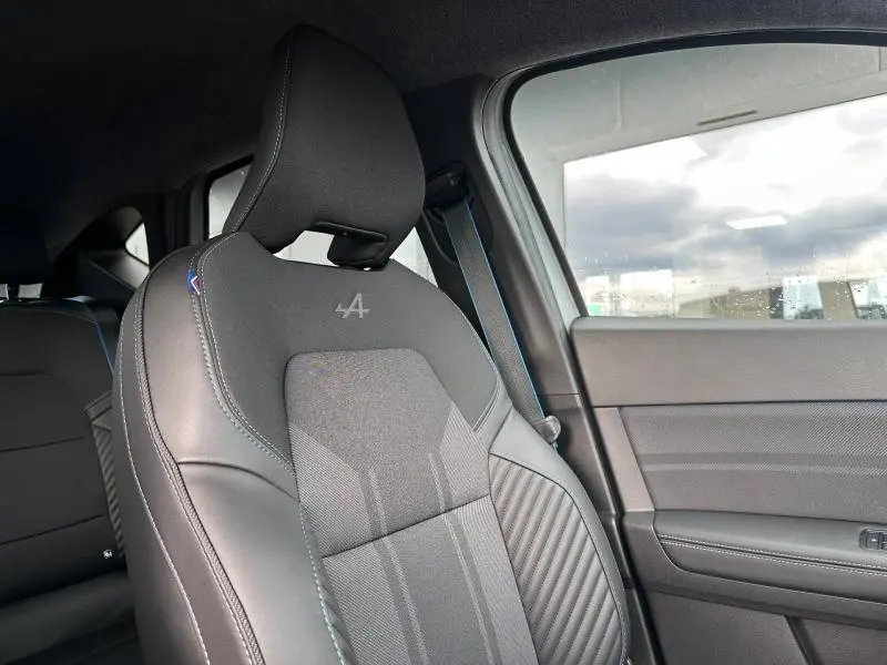 Gros plan sur le siège avant droit du Renault Captur 2026 esprit Alpine, avec logo brodé et surpiqûres bleues visibles.