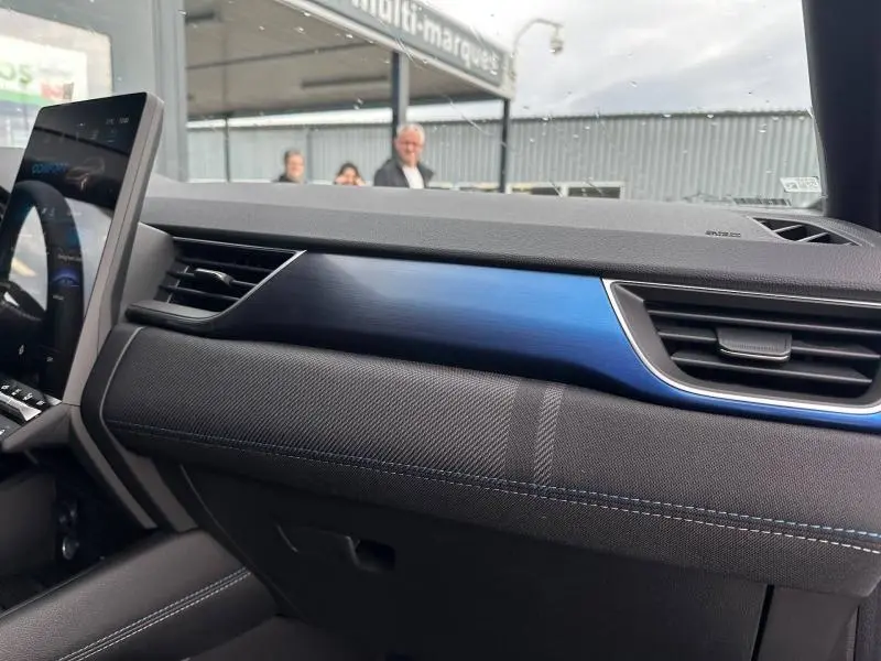 Intérieur du Renault Captur 2026, vue côté passager sur tableau de bord avec insert bleu et aérateurs noirs.