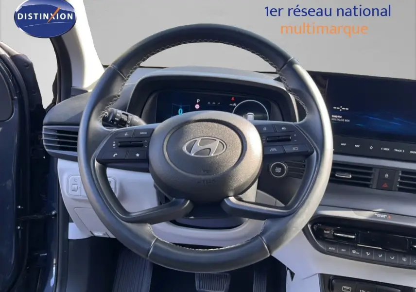 Vue intérieure centrée sur le volant cuir multifonction de la Hyundai i20 2025, avec tableau de bord digital et écran tactile.