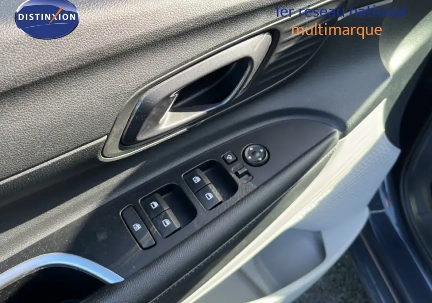 Gros plan sur la commande des vitres et la poignée intérieure côté conducteur d'une Hyundai i20 gris Aurora Metal.