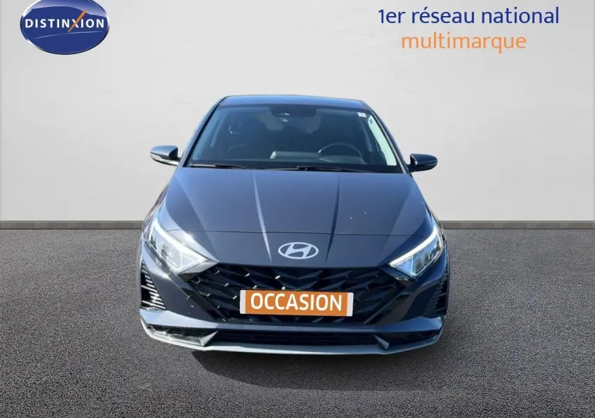 Vue avant d'une Hyundai i20 1.0 T-GDI gris Aurora Metal avec calandre noire et phares LED allumés.