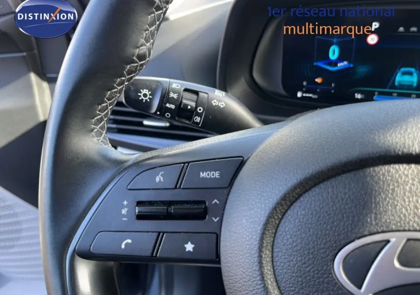 Gros plan sur le volant gris noir de la Hyundai i20 2025, avec commandes multifonctions et tableau de bord digital en arrière-plan.