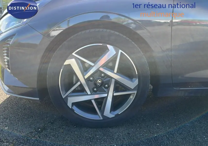 Gros plan sur la roue avant gauche d’une Hyundai i20 gris Aurora Metal avec jante alliage au design géométrique.