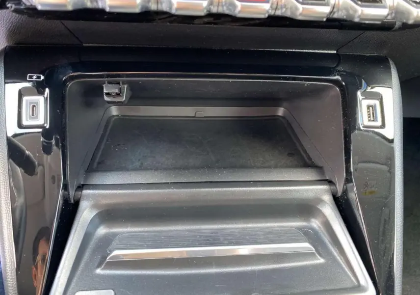 Vue rapprochée du compartiment central avec prises USB et finition noire brillante dans une Peugeot 208 2021.