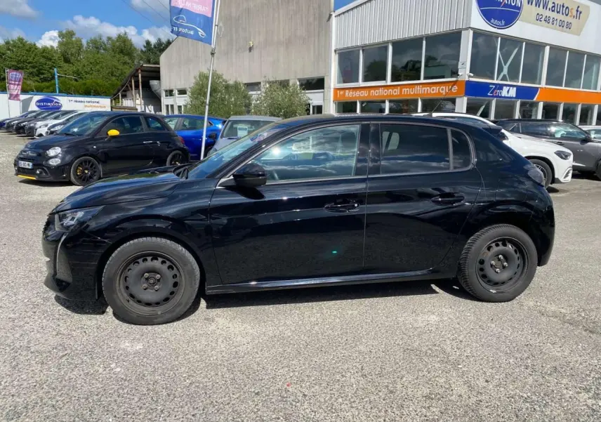 Peugeot 208 noire vue de profil côté gauche, avec jantes acier et carrosserie brillante, stationnée en extérieur.