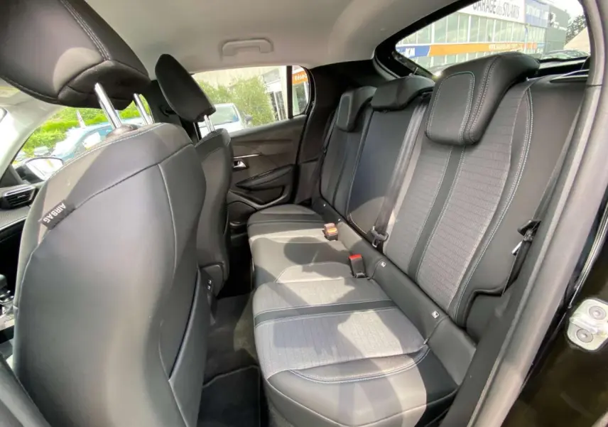 Vue intérieure côté droit des sièges arrière noirs avec surpiqûres blanches d'une Peugeot 208 noire de 2021.