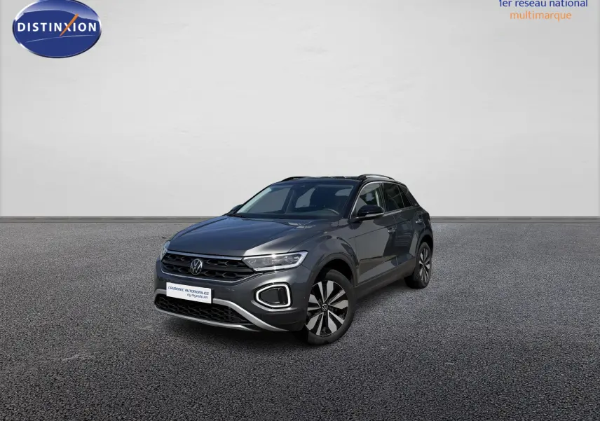 Volkswagen T-Roc gris en 3/4 avant droit, avec barres de toit noires et jantes distinctives.