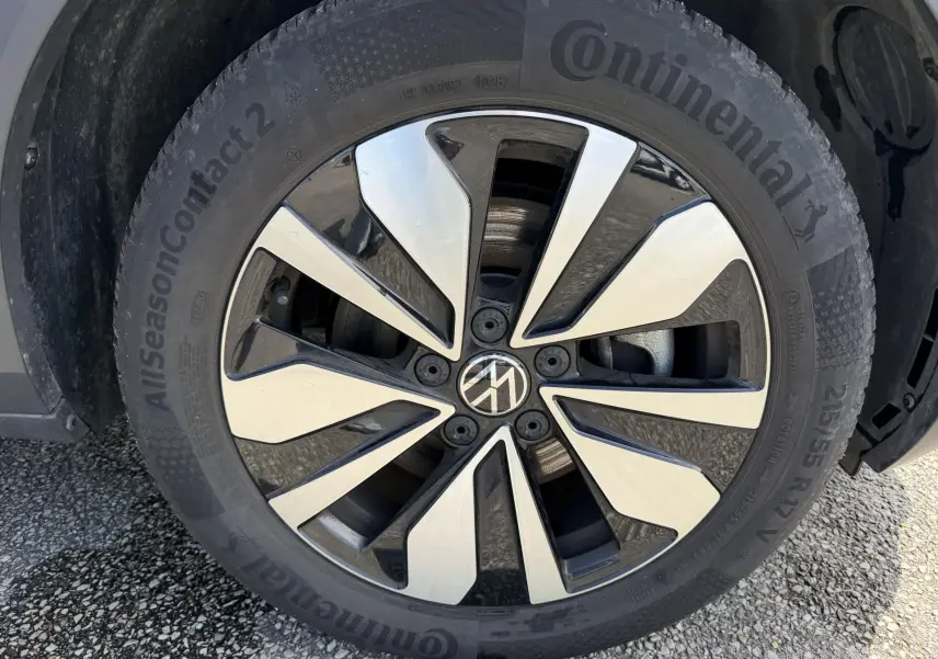 Gros plan sur la roue avant gauche du Volkswagen T-Roc gris, mettant en valeur la jante alliage bicolore et le pneu Continental.