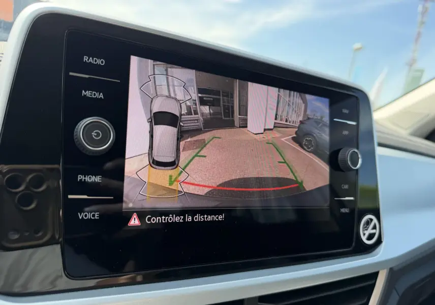 Écran tactile intérieur montrant la caméra de recul du Volkswagen T-Roc gris avec guidage de trajectoire en parking.