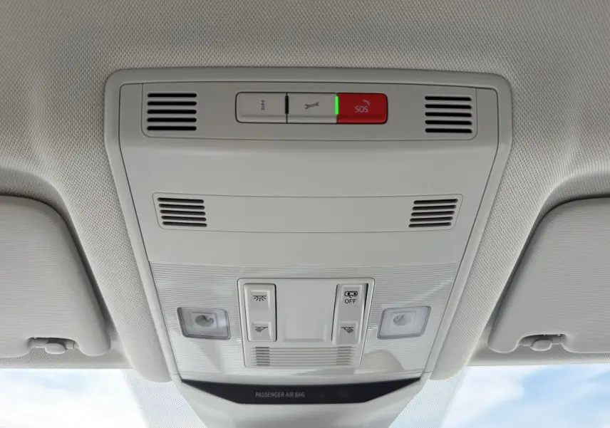 Vue intérieure du plafonnier gris clair du Volkswagen T-Roc 2025 avec commandes d'éclairage et bouton SOS.