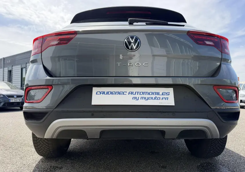 Vue arrière centrée d'un Volkswagen T-Roc gris 2025 avec feux rouges et barres de toit noires visibles.