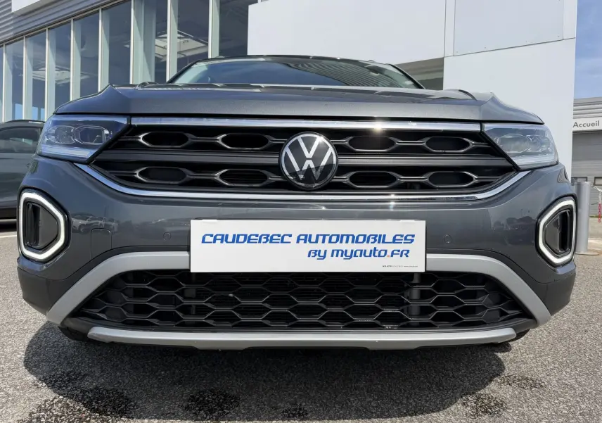 Vue frontale rapprochée du Volkswagen T-Roc gris 2025 avec calandre noire et éclairage LED distinctif.