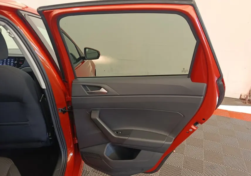 Porte arrière droite ouverte d’une Volkswagen Polo orange 2020, intérieur tissu noir et panneau de porte gris.