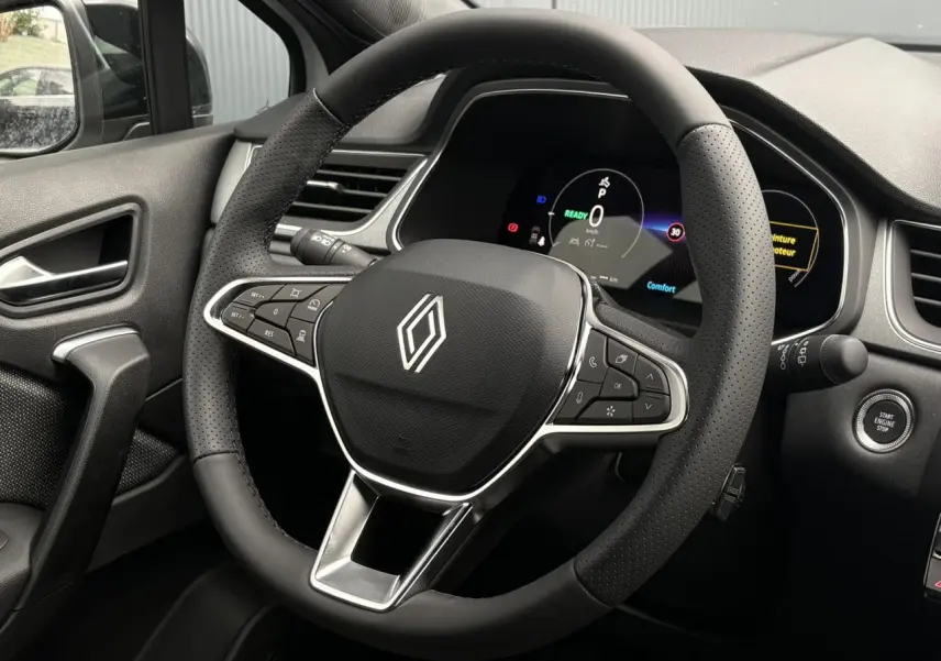 Vue rapprochée du volant noir perforé et du tableau de bord numérique du Renault Captur hybride 2026.