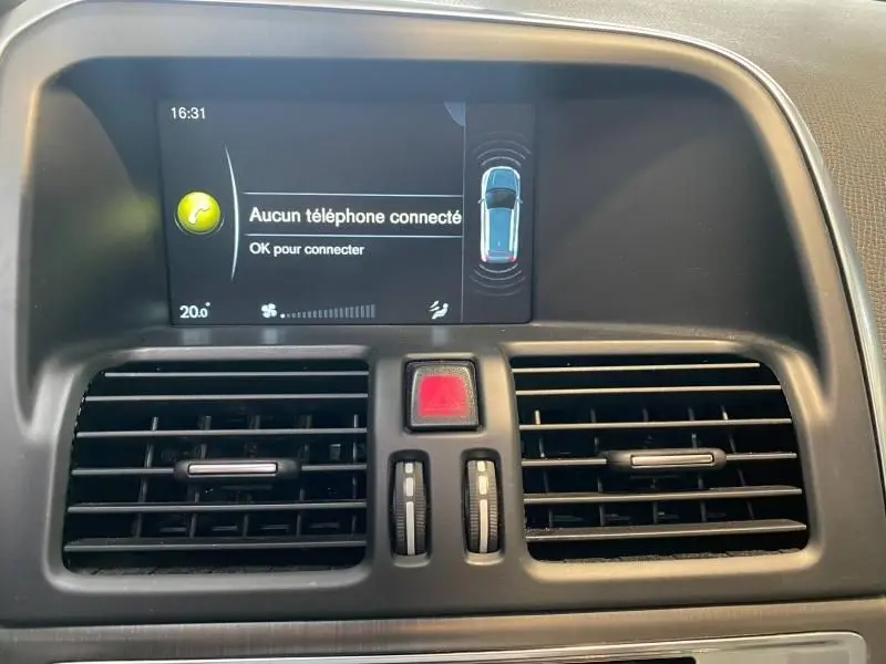 Vue rapprochée de l'écran multimédia et des aérateurs centraux noirs du tableau de bord du Volvo XC60 argenté de 2015.