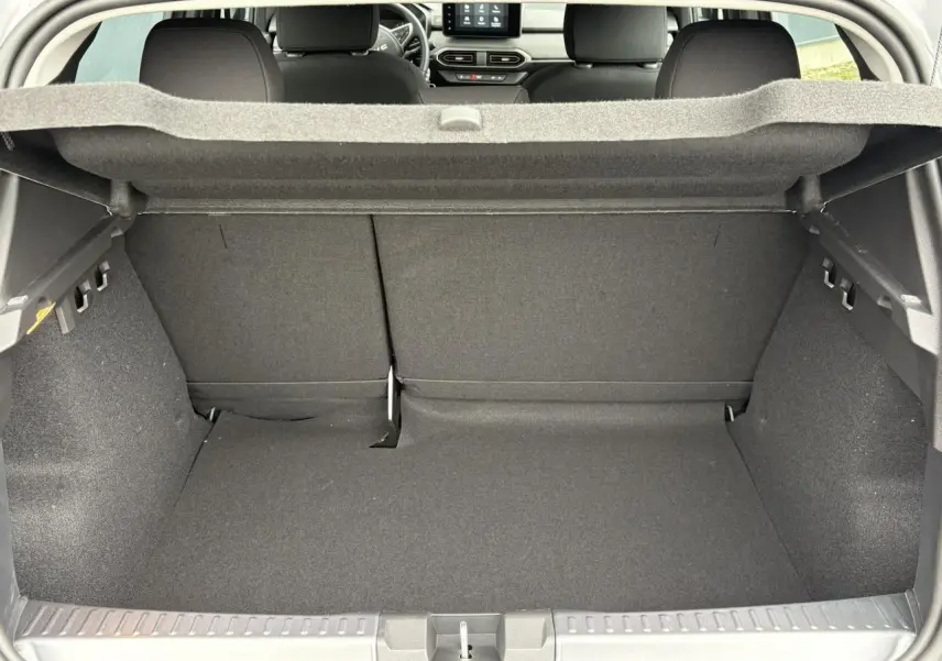 Coffre ouvert du Dacia Sandero Stepway gris Schiste, vue arrière montrant l'espace de chargement et les sièges arrière.