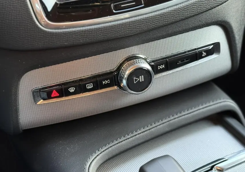 Gros plan sur la commande multimédia centrale du Volvo XC90 blanc Crystal 2024 avec finition Chrome et détails noirs.