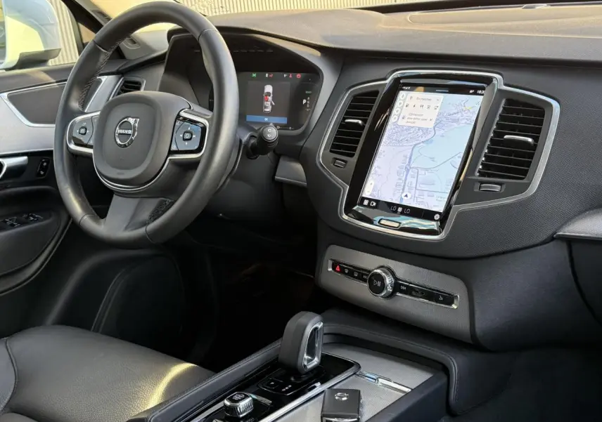 Vue intérieure côté conducteur du tableau de bord et console centrale du Volvo XC90 2024 avec écran tactile vertical et volant cuir noir.