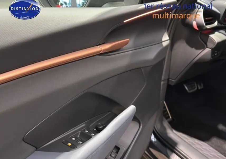 Vue intérieure côté conducteur de la CUPRA TERRAMAR 2025, mettant en valeur la garniture grise et la poignée cuivrée.