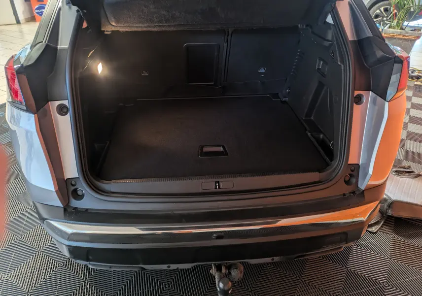 Vue arrière du coffre ouvert d'un Peugeot 3008 gris Arthense, montrant l'espace de rangement et l'éclairage intérieur.