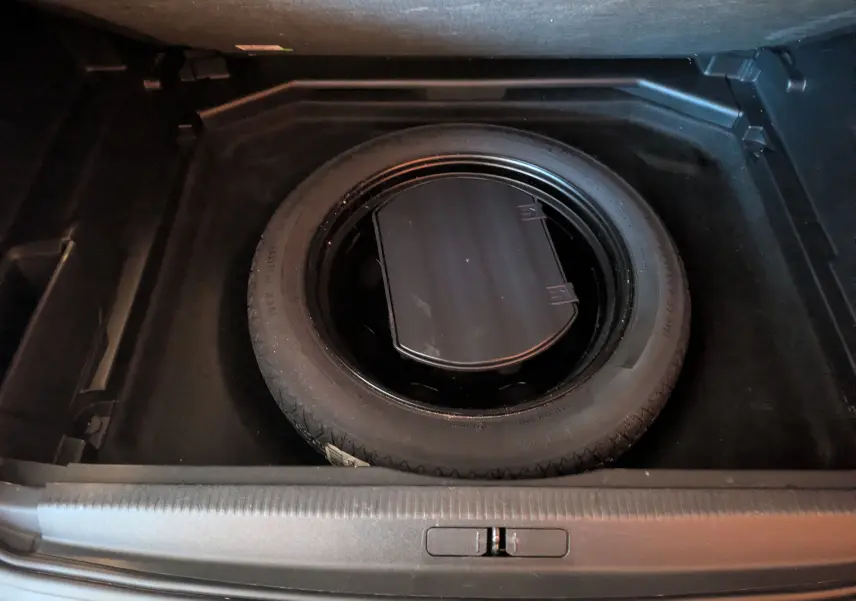 Vue plongeante sur la roue de secours noire dans le coffre d’un Peugeot 3008 gris Arthense de 2019.