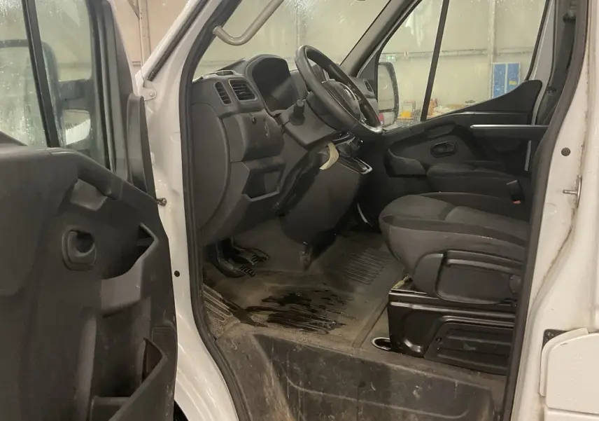 Vue intérieure côté conducteur du Renault Master blanc 2020, montrant le tableau de bord et les sièges avant en tissu noir.