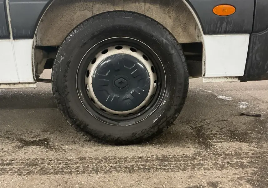 Gros plan sur la roue arrière droite d’un Renault Master cabine approfondie blanc, avec pare-boue et feu latéral orange.