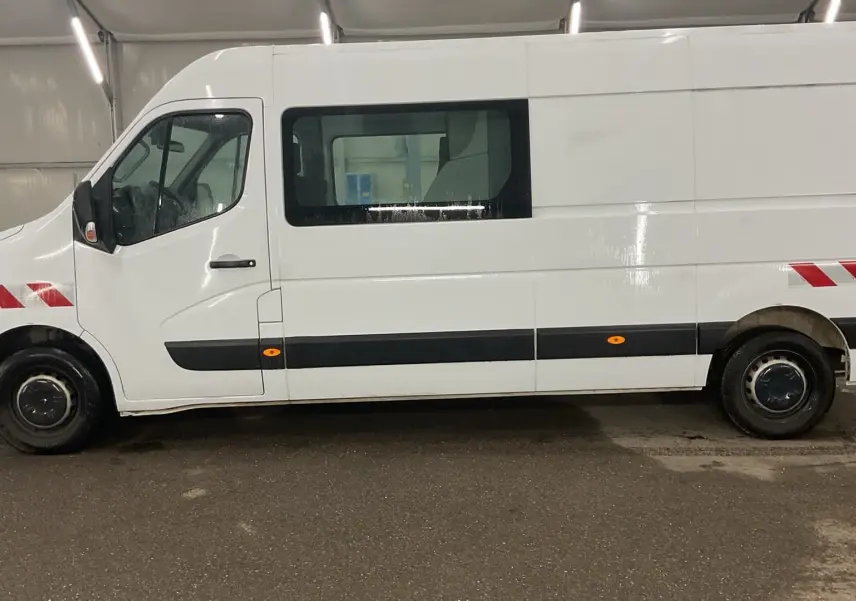 Vue de profil côté gauche d’un Renault Master blanc avec marquages rouges réfléchissants sur les ailes avant et arrière.