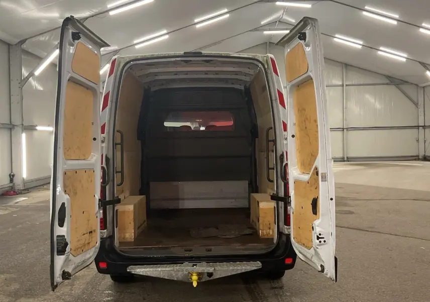 Vue arrière du Renault Master blanc avec portes arrière ouvertes, montrant l'espace de chargement boisé et un attelage.