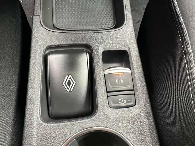 Vue rapprochée de la console centrale du Renault Captur 2026 avec bouton frein à main électronique et logo Renault noir mat.