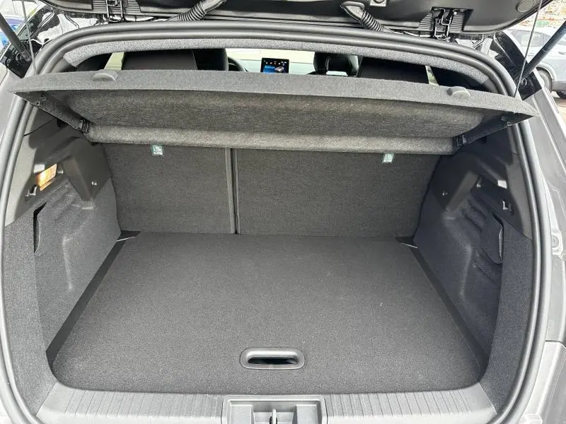 Vue intérieure du coffre ouvert du Renault Captur 2026 hybride, avec habillage gris foncé et cache-bagages relevé.