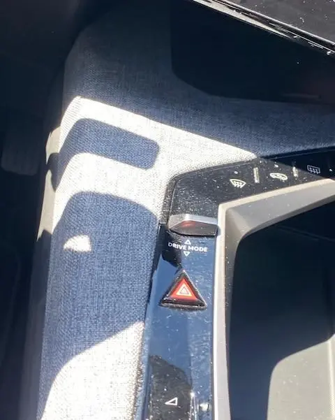 Gros plan sur la console centrale du Peugeot 3008 noir, montrant le bouton Drive Mode et la commande des feux de détresse.