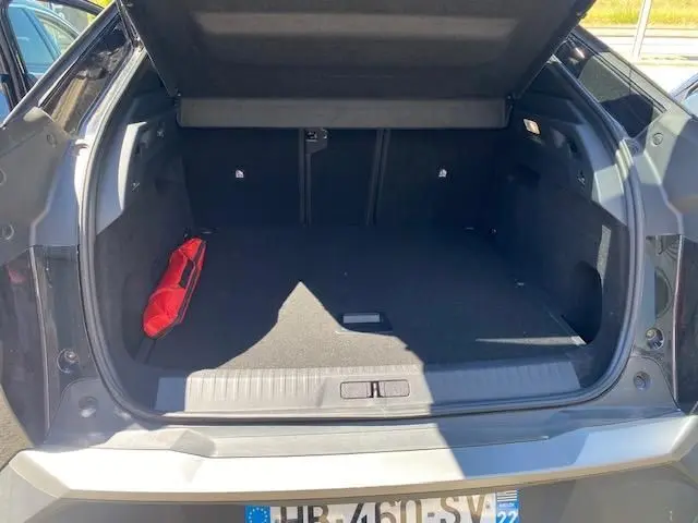 Coffre ouvert du Peugeot 3008 noir vue arrière, espace de chargement vide avec trousse de secours rouge sur le côté gauche.