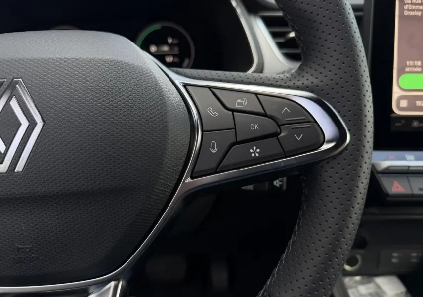 Gros plan sur le volant perforé noir du Renault Captur 2026 avec commandes multifonctions et logo central chromé.