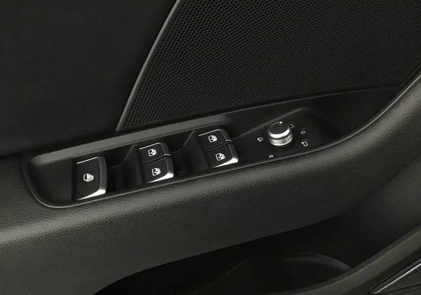 Gros plan sur la commande des vitres et rétroviseurs côté conducteur de l'Audi A3 Cabriolet noire 2020.