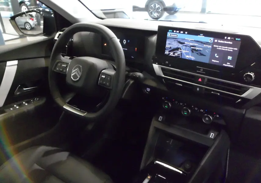 Vue intérieure côté conducteur de la Citroën C4 Hybride 2025, avec tableau de bord numérique et écran tactile central.