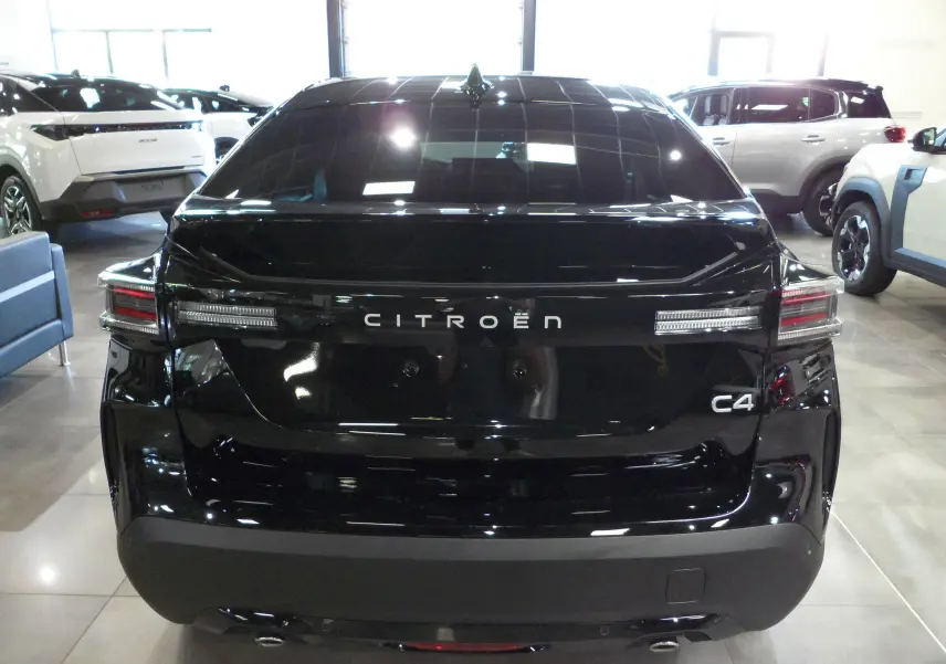 Vue arrière d'une Citroën C4 noire Perla 2025 avec feux LED et logo bien visibles dans un showroom.