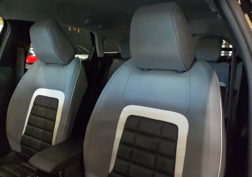 Gros plan sur les sièges avant en cuir noir et gris du Citroën C4 Hybride 136 e-DCS6 Max 2025, intérieur élégant.