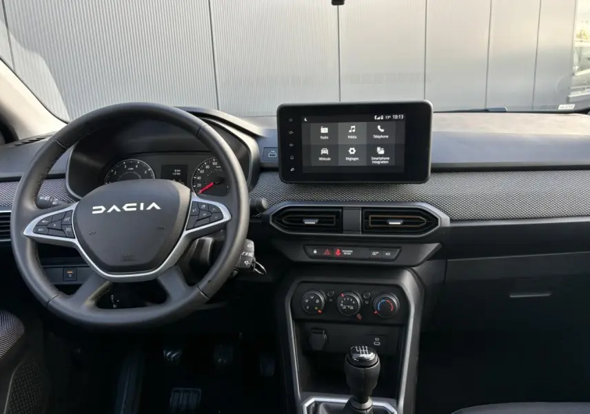 Intérieur de la Dacia Sandero Stepway 2025, vue frontale du tableau de bord avec écran tactile et volant noir.