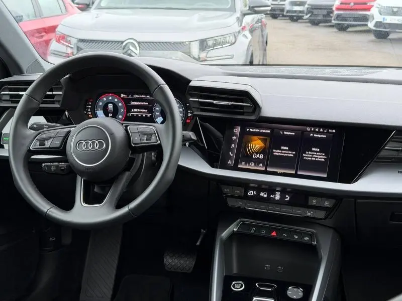 Vue intérieure du tableau de bord et volant multifonction noir de l'Audi A3 Sportback 2024, écran tactile central allumé.