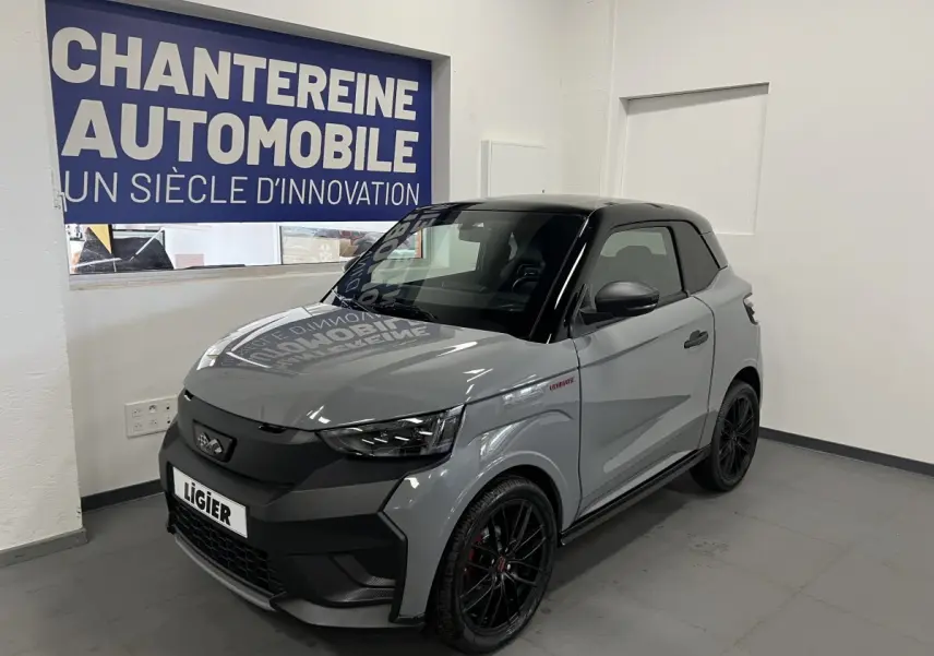 Vue 3/4 avant droite d'une Ligier JS50 gris clair avec toit noir et jantes noires en showroom.