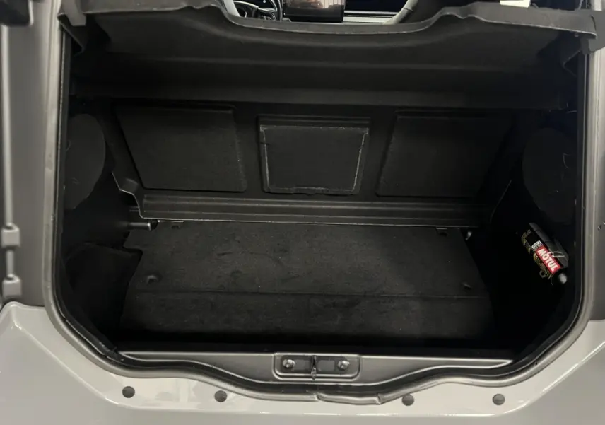 Vue plongeante sur le coffre noir ouvert d’une LIGIER JS50 bleu 2026, montrant l’espace de rangement intérieur.