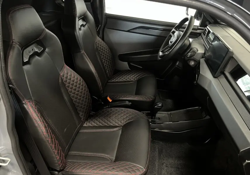 Vue intérieure côté conducteur de la Ligier JS50 0.5 REVO D+ Ultimate avec sièges noirs et surpiqûres rouges.